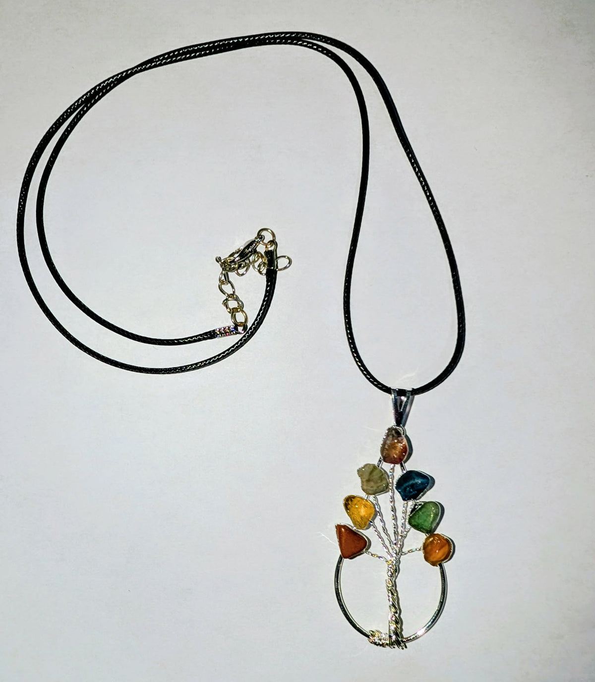 Silver-plated chakra tree branch pendant featuring colorful stones inspired by the seven chakras in a nature-inspired design.